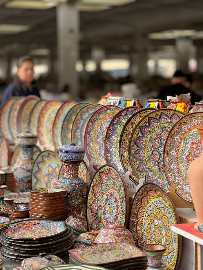 Vibrant display of handcrafted ceramic plates and vases at an outdoor market.